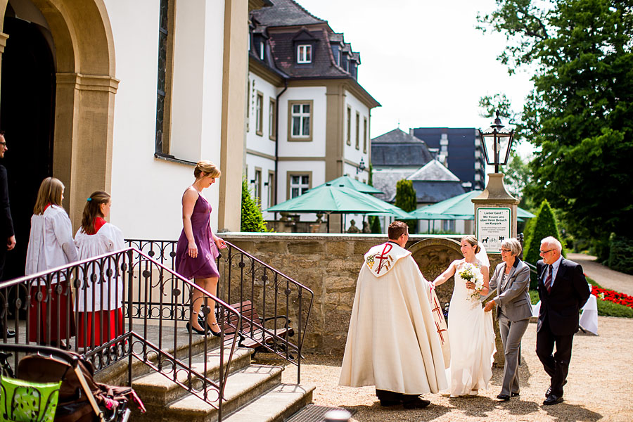 Pfarrer empfängt Braut vor der Kirche