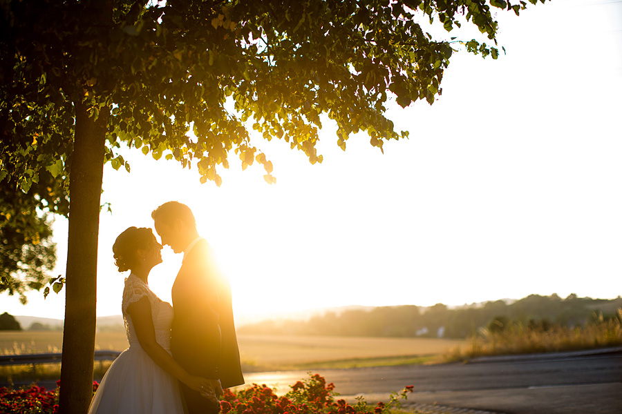 Braut und Bräutigam küssen sich im Sonnenuntergang auf der Hochzeit in Gettenbach