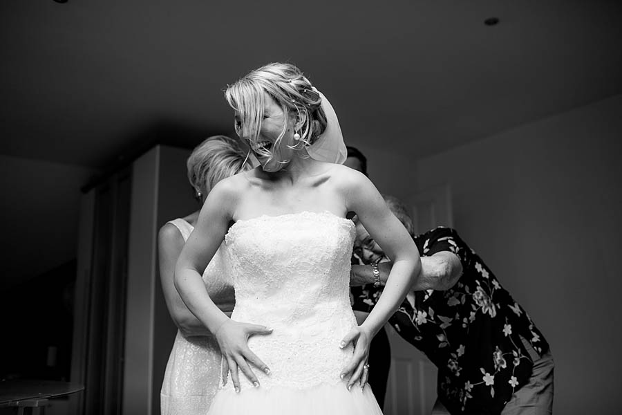 Hübsche Braut lacht beim schließen des Kleids