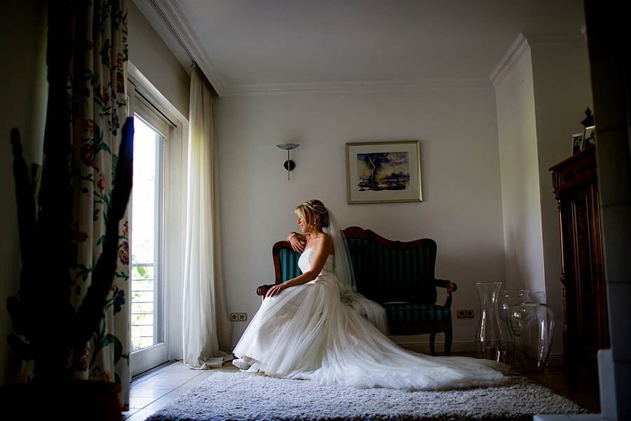 Hübsche Braut sitzt mit großem Kleid an Fenster