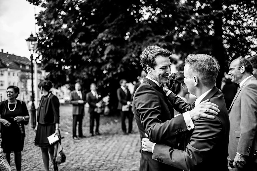 Bräutigam mit Freund freut sich vor der Kirche