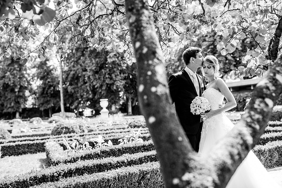 Braut und Bräutigam stehen unter Baum und küssen sich Orangerie Mondorf 