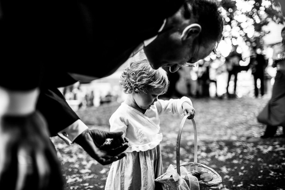 Blumenkind schaut in Blumenkorb auf Hochzeit schwarz weiss 