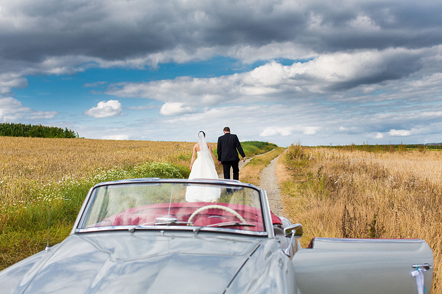 Brautpaar mit Mercedes SL Oldtimer auf Wiese