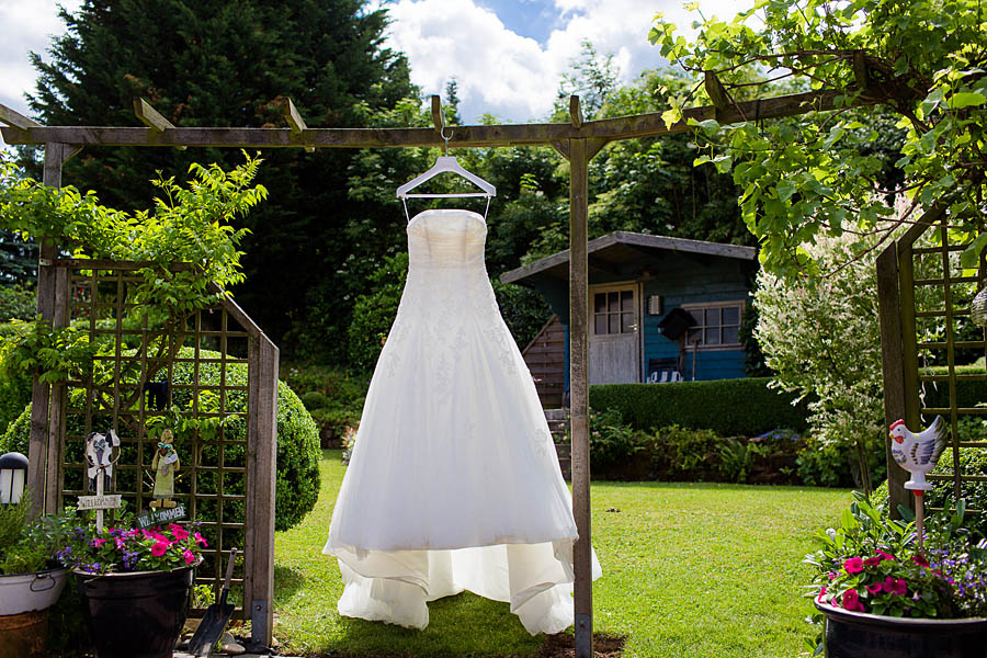 Schönes Brautkleid hängt im Garten bei Sonne