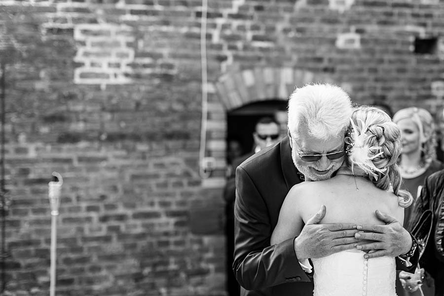 Der Vater des Bräutigams umarmt die Braut