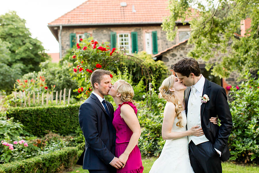 Braut und Bräutigam und befreundetes Paar küsst sich
