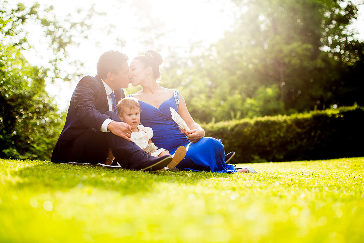 Familie auf Hochzeit küsst sich auf der Wiese mit Kind