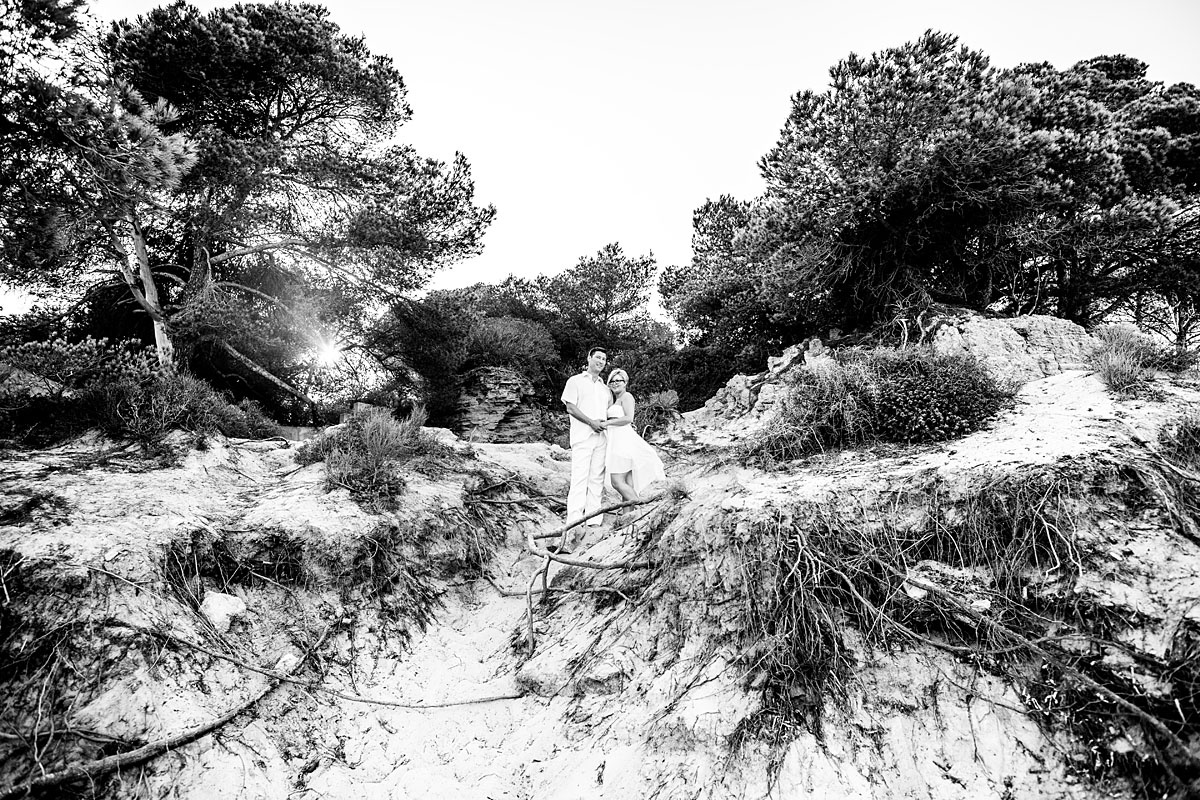 schönes Paar steht in weißen Kleidern am Strand vom Mallorca romantisch bei Sonnenuntergang Schwarz Weiß foto